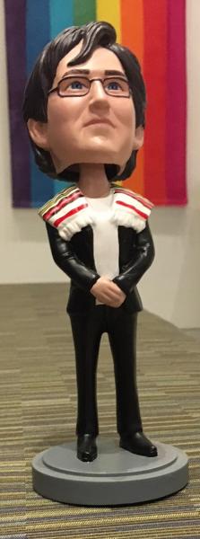 Rabbi Kleinbaum as a bobble-head doll, photographed in the CBST lobby in front of the rainbow flags